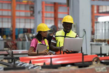 Male and female factory worker working and using laptop computer inspecting quality of production line conveyor in industry factory. Workers inspector checking manufacturing process in plant