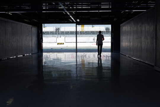 Silhouettes of a man entering a race car racing circuit paddock.