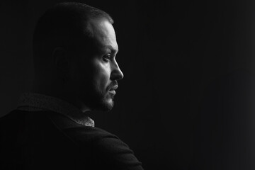Fabulous at any age. Profile portrait of charismatic 40-year-old man posing over black background. Short haircut. Classic, smart casual style. Close up. Copy-space. Black and white studio shot - obrazy, fototapety, plakaty