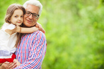 Family values concept. Portrait of stylish and fashionable grandfather with his grandchild sitting in his hands. Close up. Copy-space. Outdoor shot