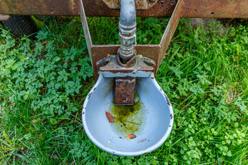 Close-up of waterer in an old mobile livestock water tank on an agricultural plot on Dutch farm, green grass and sunlight in background, sunny day in Sweikhuizen, South Limburg, Netherlands
