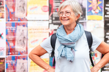 Fototapeta premium Happy carefree senior woman tourist walking in Seville, Spain holding a backpack enjoying vacation trip freedom, healthy lifestyle in retirement