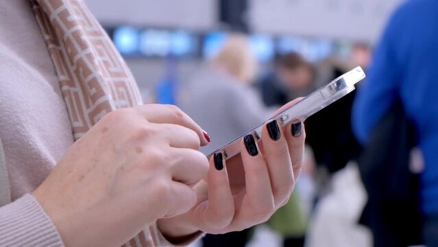 Close-up. People in international airport. Female traveler look at phone, search for boarding pass or flight cancelation information. 4K