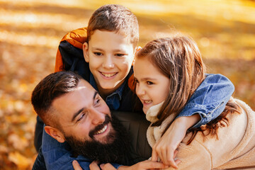 Fototapeta premium Single father having fun in the colorful park with his son and daughter. Autumn day
