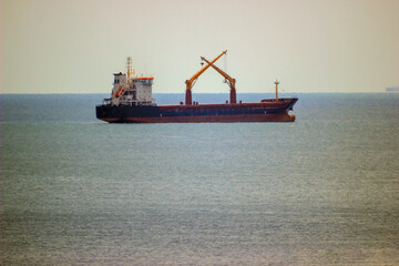 steel ship on the horizon in the Black Sea with crossed cranes	
