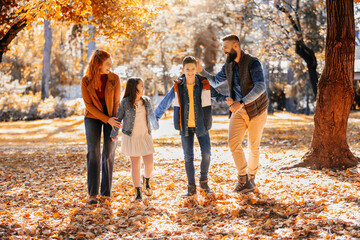 Happy family walking in the park on a sunny fall day. Colorful park.
