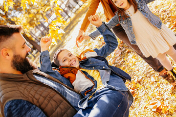 Fototapeta premium Parents tickle their children. Sunny autumn day in the colorful park