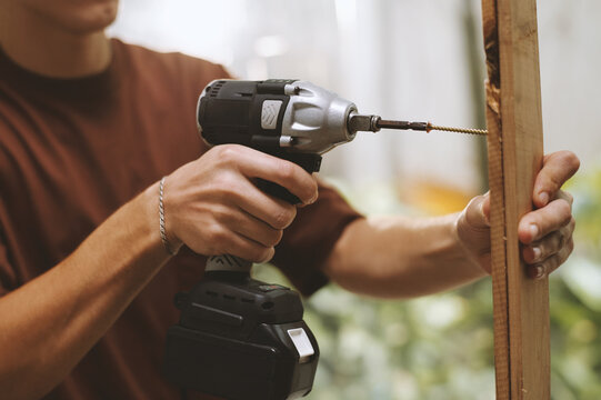 Cropped image of man drilling holes in wooden plank