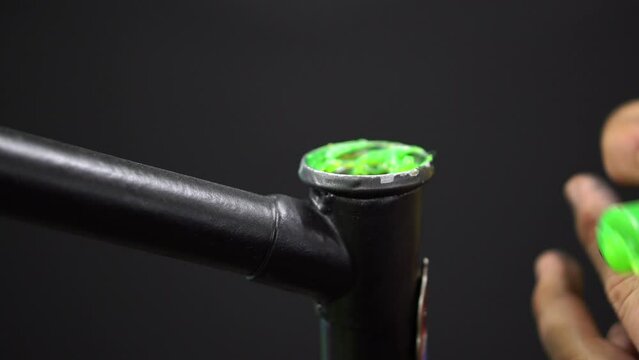 A mechanic in the workshop repairs an old frame of a classic bicycle. Replacing the grease and bearing in the headset, installing the fork in the frame, tightening the nut and the headset cone.