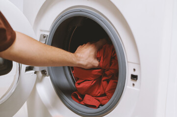 Cropped image of man taking clean shirts out of washing machine