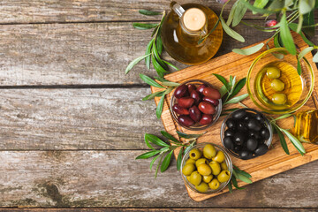 A set of green, red and black olives on  background. Various types of olives in bowls and fresh olive leaves. Vegan. Olive fruits. Place for text. Copy space.