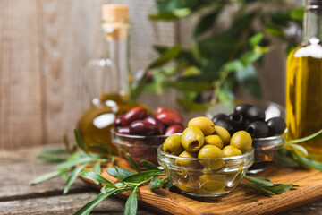 A set of green, red and black olives on  background. Various types of olives in bowls and fresh olive leaves. Vegan. Olive fruits. Place for text. Copy space.