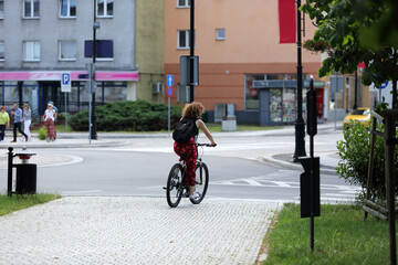 Kobieta jedzie rowerem po chodniku w mieście.