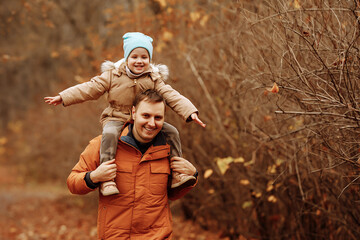 Happy family father and daughter on a walk in the autumn leaf fall in the park. Concept of fatherhood, adventure and family with one child.