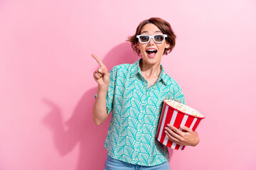 Portrait of funky impressed girl hold popcorn indicate finger empty space watch movie 3d glasses...