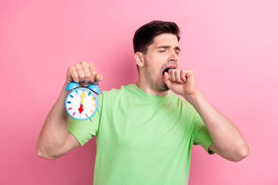 Photo of young tired funny guy show clock hand mouth yawning wear green casual t shirt early morning isolated on pink color background
