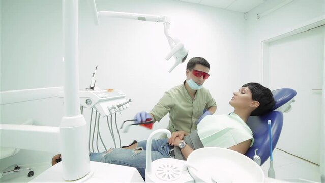 Dentist puts himself and girl lying in the dental chair protective red glasses