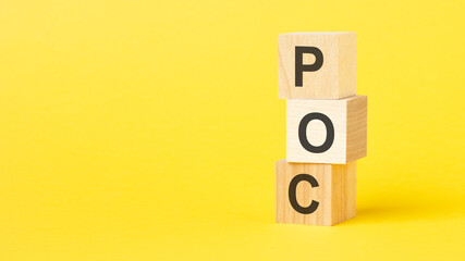 wooden blocks with the text POC - short for Proof of Concept on a bright yellow background