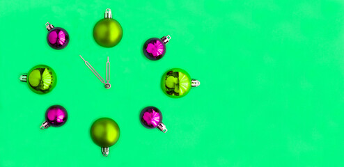 Christmas clock from green and pink bead on the green background.  Copy space.