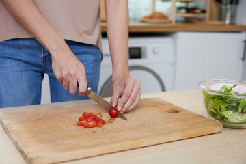 close up young woman hands cutting tomato and cooking salad in the kitchen