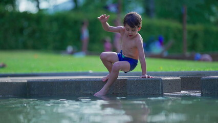 Child entering swimming pool during summer day. Excited kid enjoying vacations