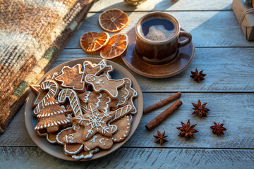 Traditional homemade gingerbread cookies and a cup of coffee on a sunny winter morning. Home comfort. Christmas mood, holiday atmosphere.