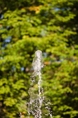 Szczyt strumienia wody tryskającego z fontanny w parku miejskim w słoneczny jesienny dzień