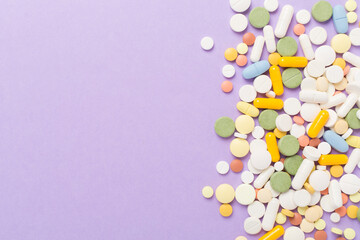 Different medical pills and capsules on color background, top view