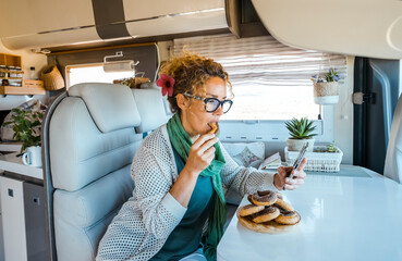 One woman eating dognuts donuts inside a modern luxury camper van. People and unhealthy sugar food....