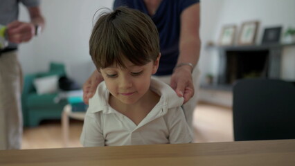 Grandmother adjusting grandson's polo collar indoors. affectionate grandma balancing child's attire