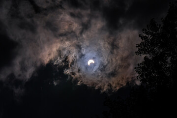 Fototapeta na wymiar wide angle of partial solar eclipse in sky lighting up clouds all around with sky dark. 