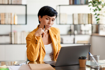 Pensive Lady Entrepreneur Thinking Looking At Laptop In Modern Office