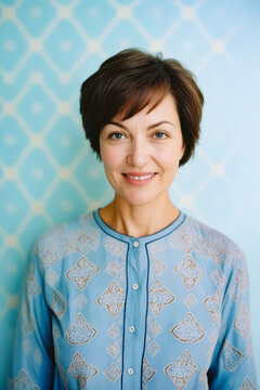 Woman with short hair smiling for picture in blue shirt.
