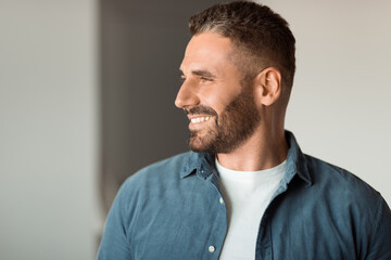 Fototapeta premium Cheerful middle aged man smiling while looking aside indoor