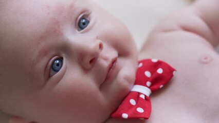 4 months old infant baby boy at changing table, detail on his head, red white dot bow over neck