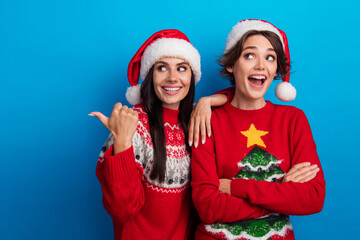 Photo of girls santa claus helpers point finger empty space x mas winter discounts isolated blue color background