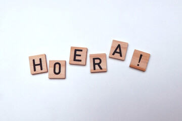 "Hooray!" which is written in Dutch as "Hoera!" in wooden blocks on a white background.