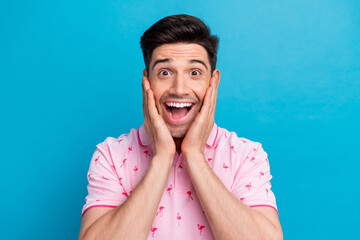 Photo of funky astonished person open mouth arms touch cheeks cant believe isolated on blue color background
