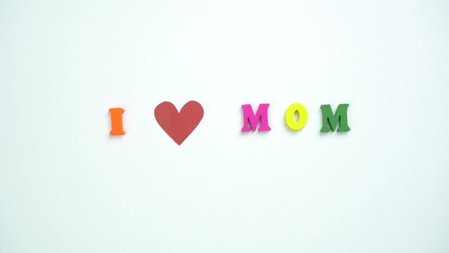 I Love Mom text from colorful wooden letters and a beating paper red heart. Congratulations on mother's day.