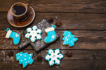 Traditional beautiful glazed gingerbread and a cup of coffee. Top view on a wooden table. Christmas mood.