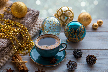 Christmas mood, holiday atmosphere. A cup of coffee, Christmas tree golden and turquoise balls, cones, star anise, cinnamon on a wooden windowsill against the background of a window 