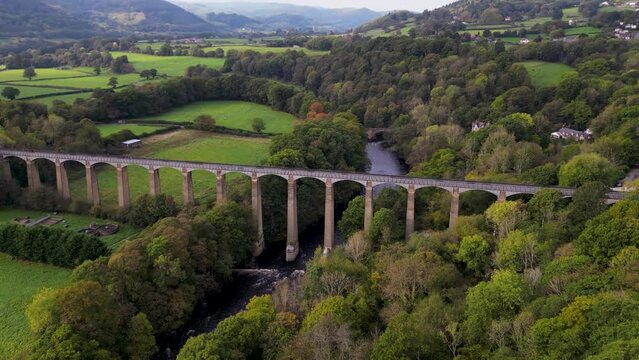 Top cinematic aerial view to the Old Welsh Pontcysyllte Aqueduct waterway aerial view rural Autumn woodlands valley. United Kingdom Aerial.  