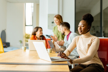 Cute Africam American woman with her young multiethnic startup team working in the modern office