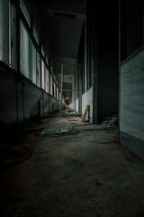 Fototapeta na wymiar Scary and dark corridor in an abandoned building. Shabby walls. Long corridor. Gloomy atmosphere.