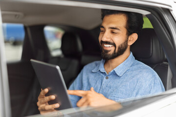 Cheerful young indian businessman checking emails while going to airport