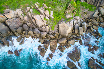 Original name(s): Bird eye drone shot of north east point beach, granite rocks, turquoise water, waves crashing, greenery, Mahe Seychelles - Powered by Adobe