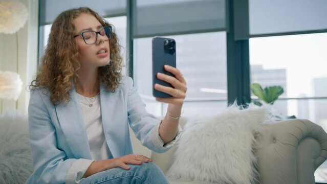 Young woman clarifying agreeing talking mobile phone. Young entrepreneur speaking on video chat using mobile front camera on cell gadget. 20s girl female manager friendly happy answering communicate