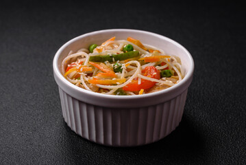 Tasty dish of Asian cuisine with rice noodles, chicken, asparagus, pepper, sesame seeds