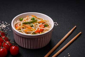 Tasty dish of Asian cuisine with rice noodles, chicken, asparagus, pepper, sesame seeds