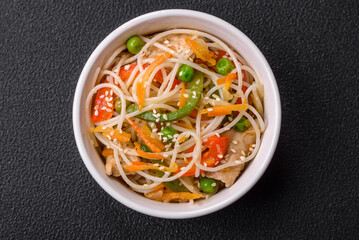 Tasty dish of Asian cuisine with rice noodles, chicken, asparagus, pepper, sesame seeds
